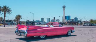 Old school car with city view in background.